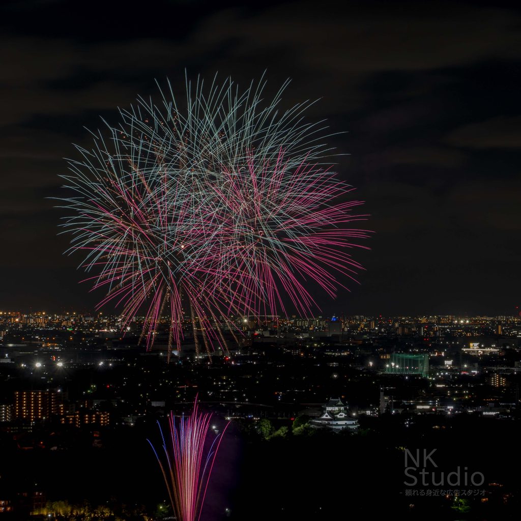 夜空に広がる色鮮やかな花火と街の灯り