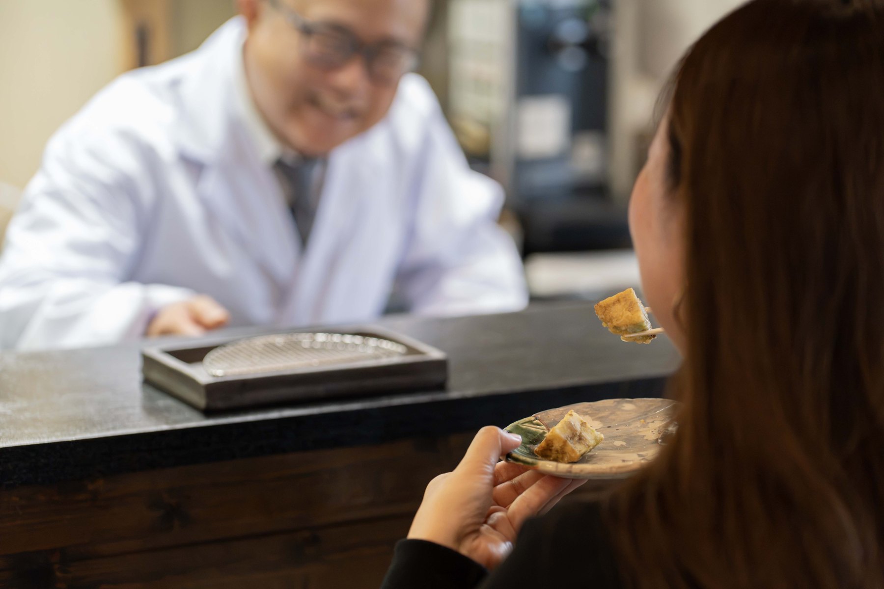 天ぷら さくのカウンターでお客様が天ぷらを味わい店主が見守る食事風景