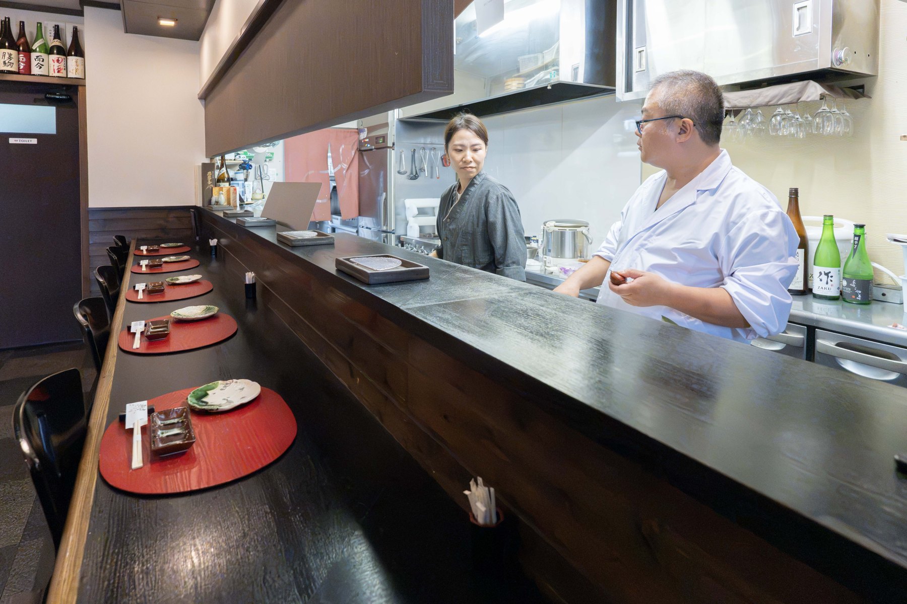 天ぷら さくのカウンター席と店内で働く二人の店舗内観